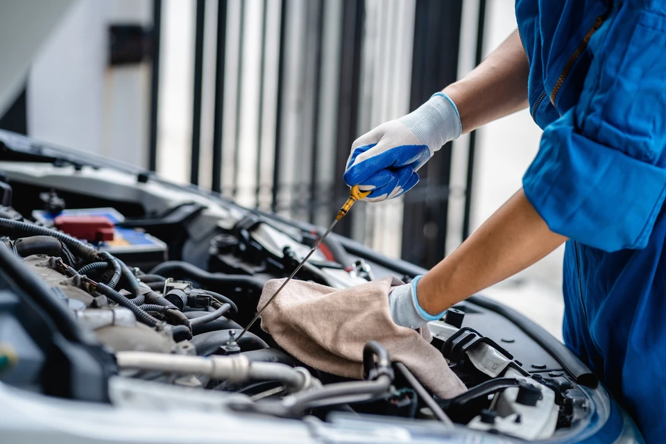 Mécanicien automobile en combinaison bleue effectuant une maintenance moteur dans un garage professionnel