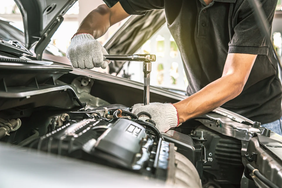 Mécanicien automobile travaillant sous le capot ouvert d'un véhicule dans un garage professionnel