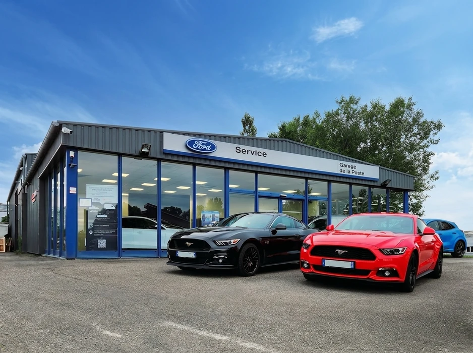 Façade extérieure d'un concessionnaire Ford "Garage de la Poste", avec deux Ford Mustang GT garées devant : une noire et une rouge