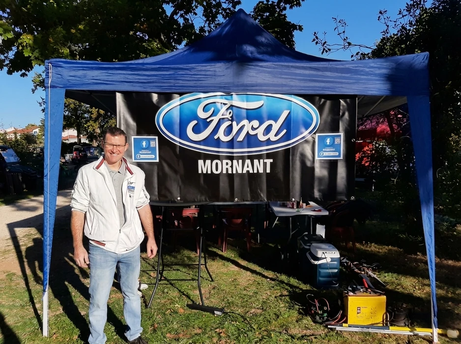 Concession automobile moderne avec vendeur en costume présentant véhicules neufs à client potentiel