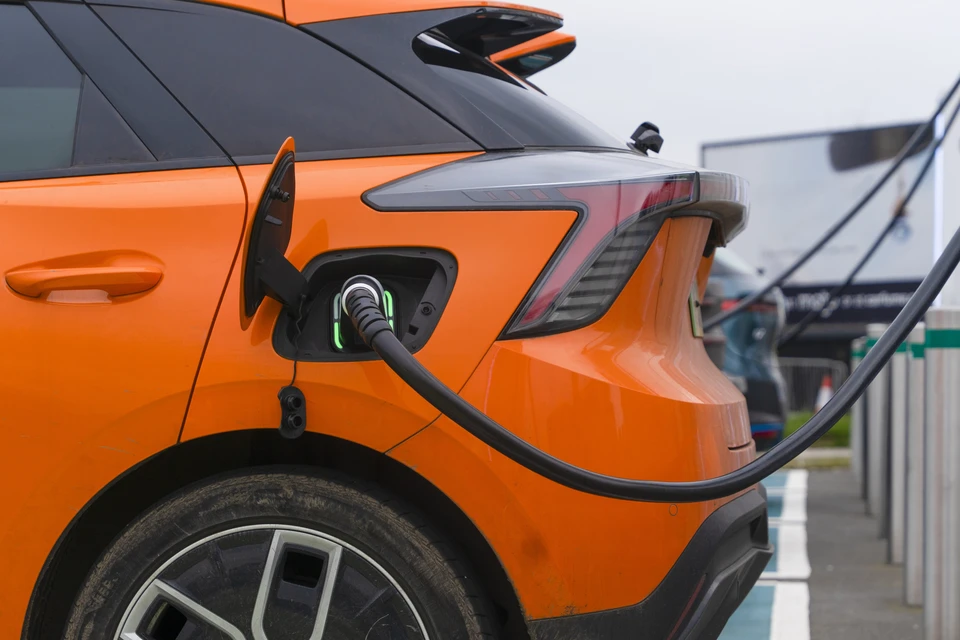 Atelier automobile en intérieur avec mécanicien portant des gants techniques noirs manipulant un composant métallique