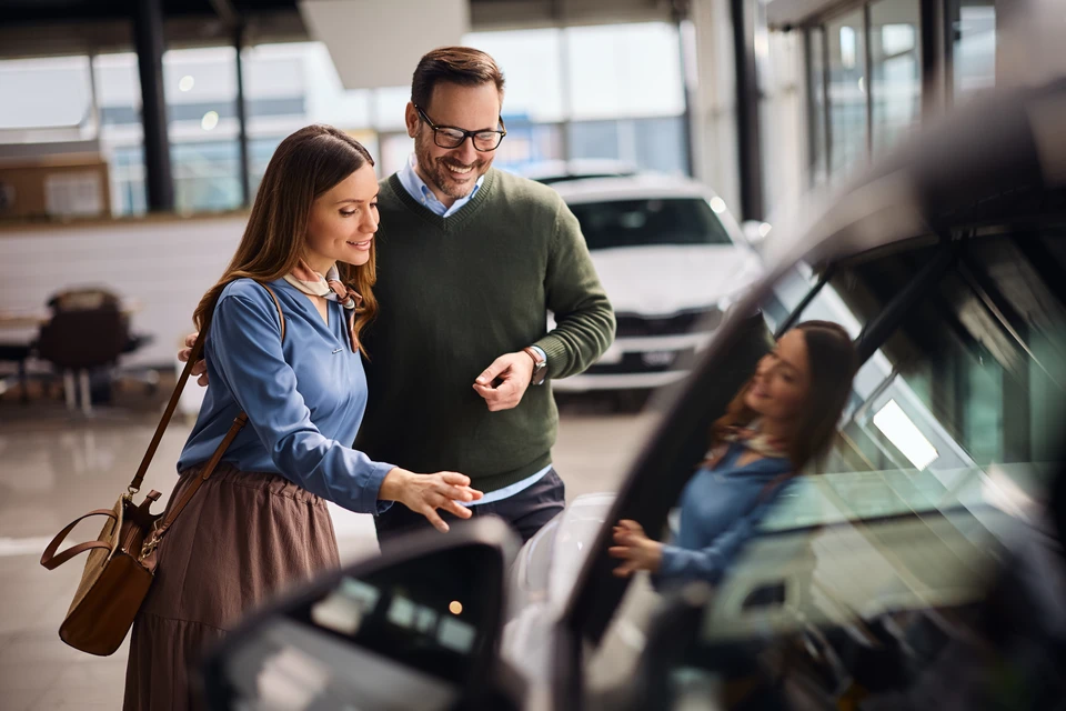 Mécanicien automobile en gants de protection vérifiant le niveau d'huile moteur avec une jauge dans un garage professionnel